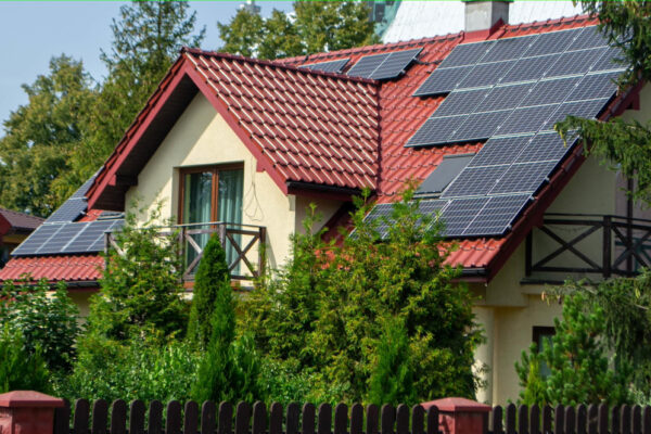 Casă cu panouri solare montate pe acoperiș roșu