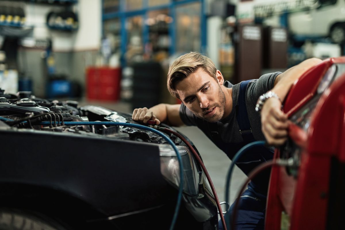 Mecanic verifică motorul mașinii în service auto